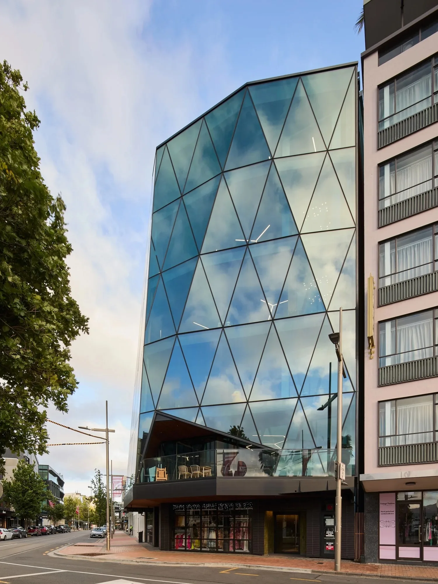 The 200 High Street building in Christchurch, its faceted glass facade reflecting the sky.